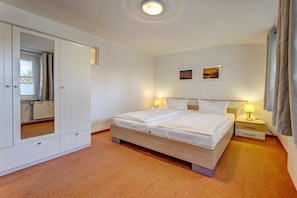 Ein Hotelzimmer mit einem Bett, Nachttischen, einem Kleiderschrank und einem Heizkörper.