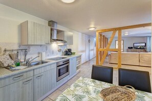 Eine moderne Küche mit Essbereich, Holzbalken und einem Fernseher im Hintergrund.