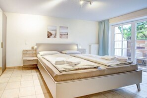 A bedroom with a bed, bedside tables, and a view of the outdoors. - Ordinger Dün Holiday Apartment 2 (St. Peter-Ording)