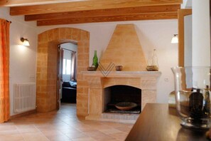 A room with a fireplace, a wooden ceiling, and a tiled floor. - Finca Tugores [1970A] (Lloseta)