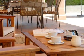 Taula de fusta amb un menú, dues tasses blanques, una cafetera i una jarra blanca.