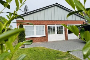 A two-story house with a brick facade, white windows, and a satellite dish. - Holiday home on the North Sea coast? (Wittmund)