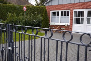 A residential area with a brick house, a hedge, and a metal fence. - Holiday home on the North Sea coast? (Wittmund)