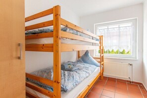 A bunk bed in a room with a window and a radiator. - Holiday apartment with 1 bedroom (Norddeich)