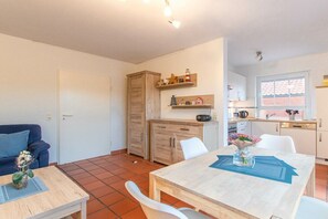 A compact living space with a dining area, kitchenette, and a sofa. - Holiday apartment with 1 bedroom (Norddeich)
