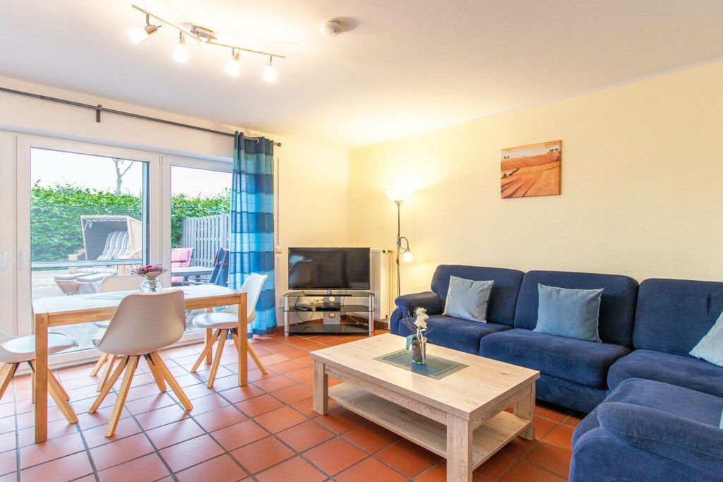 A living room with a sofa, a coffee table, a TV, and a dining area with chairs and a table.