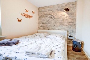 Een slaapkamer met een bed, een aan de muur bevestigd schiprad en een emmer op de vloer.