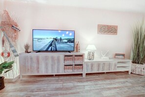 A living room with a television, a white cabinet, a lamp, and a plant. - Villa by the sea Apartment 4 (St. Peter-Ording)