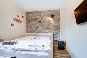 A bedroom with a bed, a wall-mounted ship's wheel, and a can of paint. - Villa by the sea Apartment 4 (St. Peter-Ording)
