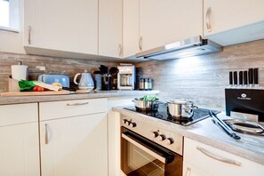 Een moderne keuken met een fornuis, oven en diverse keukenapparaten.