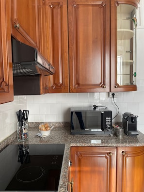 Una cucina con mobili in legno, un forno a microonde, un tostapane e un bollitore.