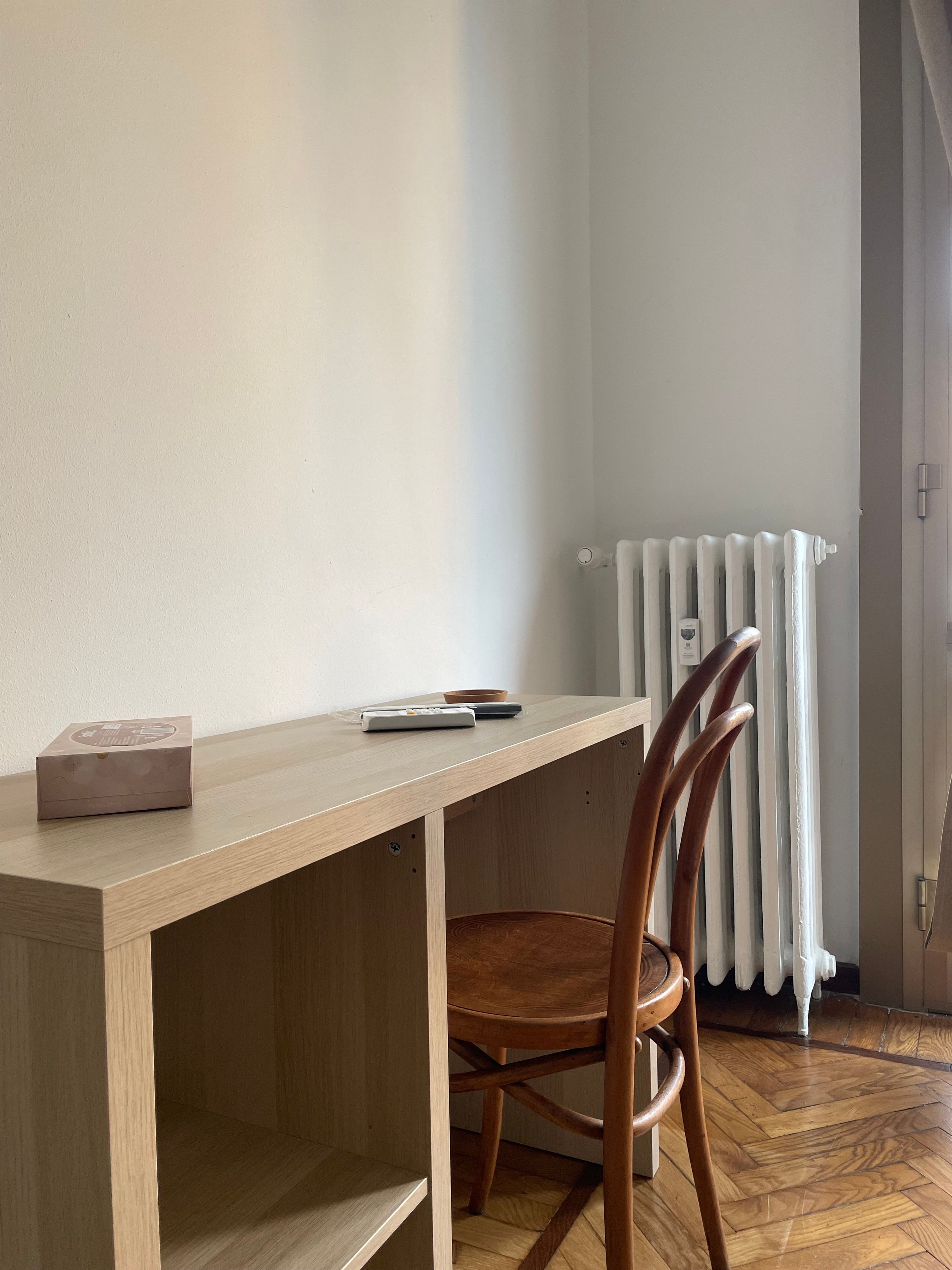 Una scrivania in legno con una sedia, un telecomando e una scatola sopra.