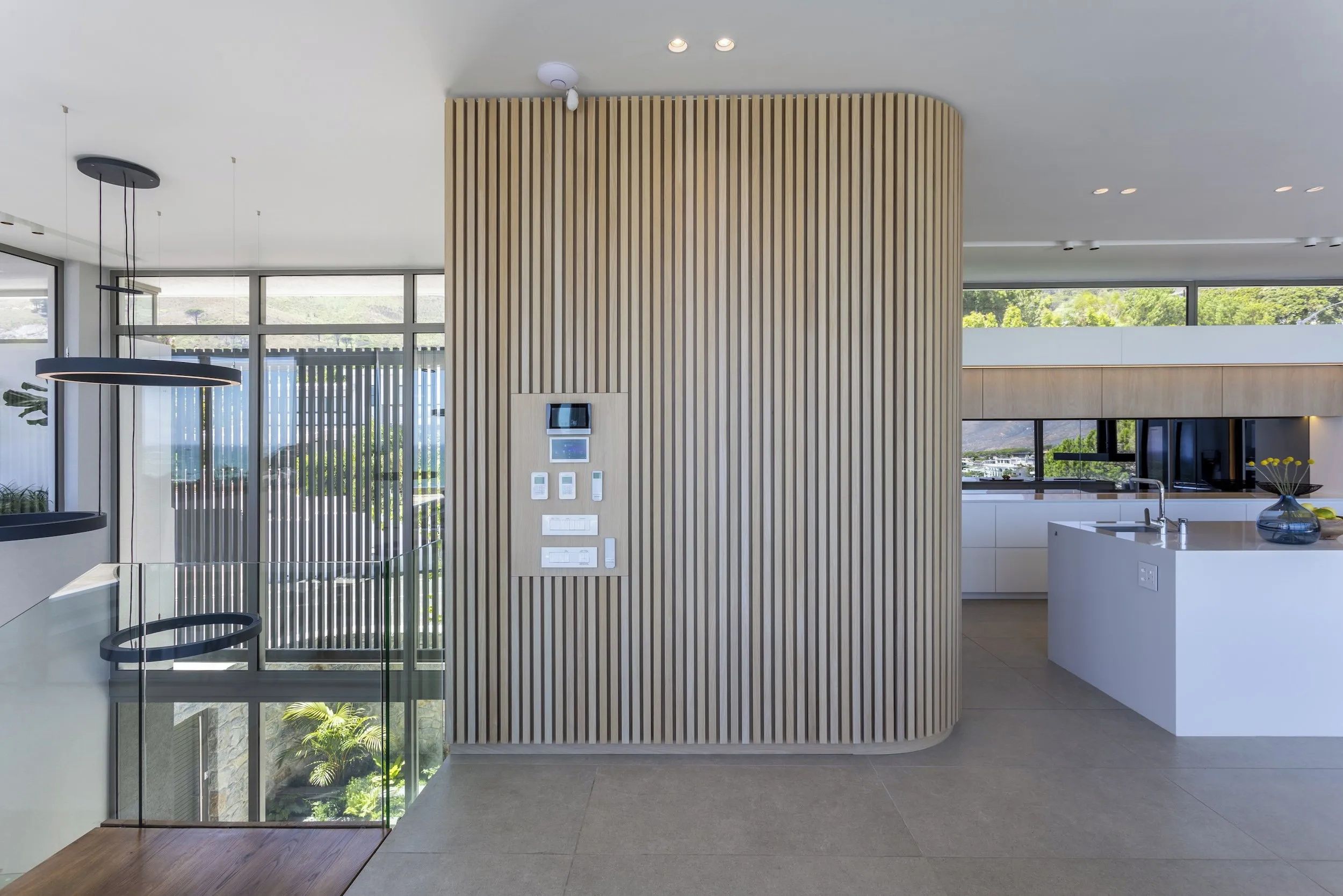 A modern kitchen with a central island, a built-in microwave, and a vertical wooden panel.