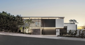 A modern two-story house with a stone facade, a garage door, and a fenced yard. - Epic Villa by Golden Sands Escape (Cape Town)