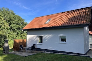 A two-story house with a red-tiled roof, a small window, and a patio with a grill and chairs. - Holiday home in Detmold with swimming pool (Detmold)