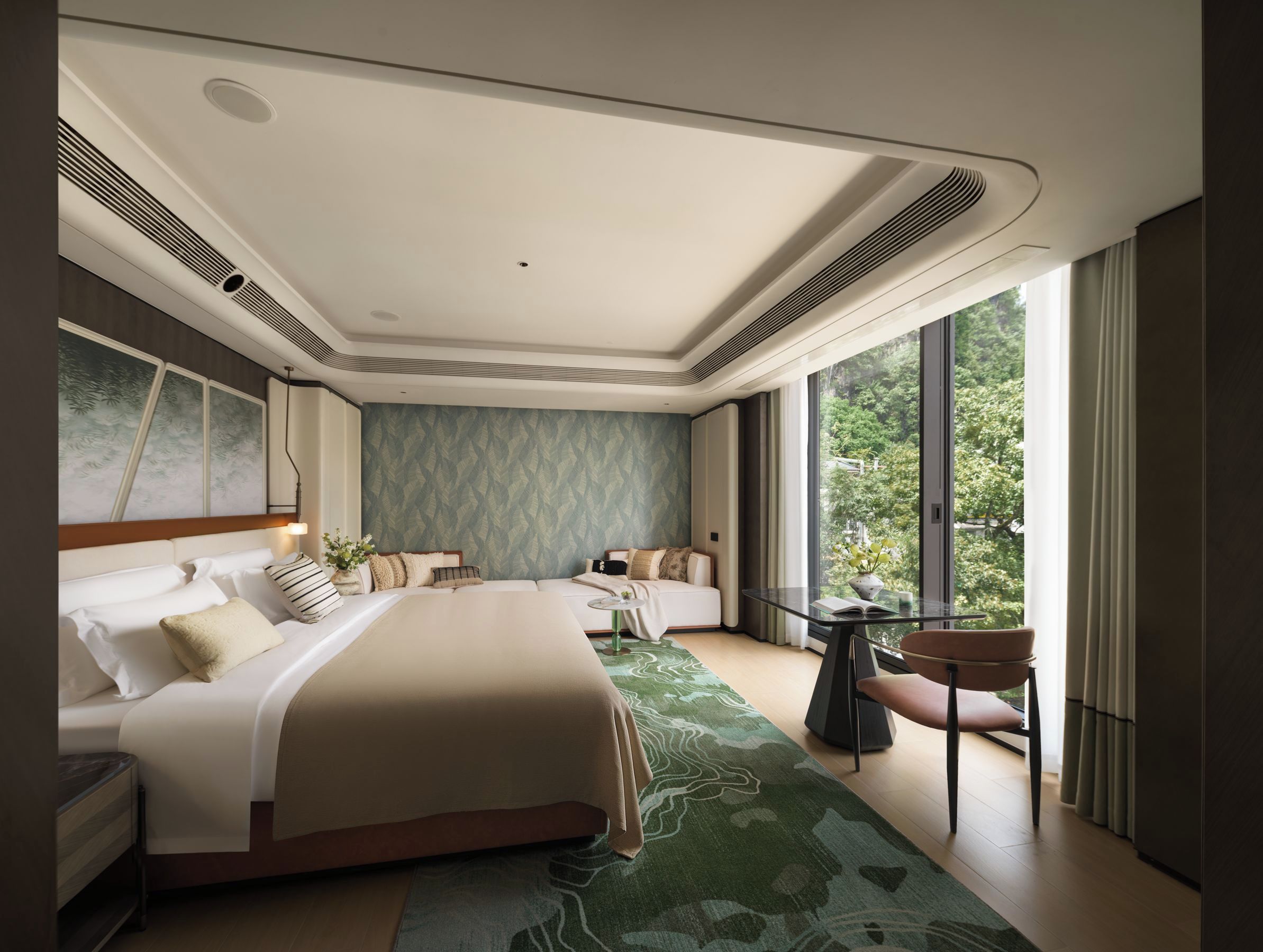 Een moderne hotelkamer met een groot bed, een klein tafeltje en uitzicht op groen.