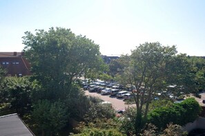 A parking lot with multiple cars and a few trees in the foreground. - Holiday apartment with 1 bedroom (Westerland)