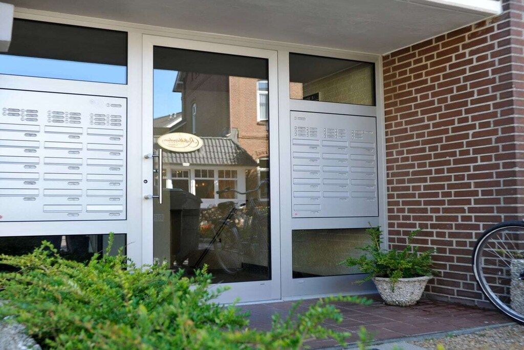 A building entrance with a glass door, a brick wall, and a bicycle parked outside.