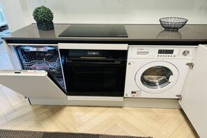 A compact kitchen with a dishwasher, oven, and built-in washing machine. - Buoy 108, Mellumweg 2, Schillig (Wangerland)