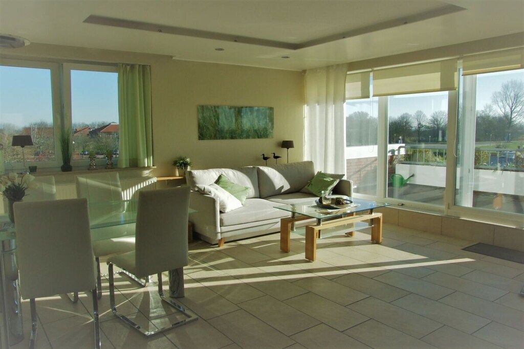 Un salon moderne avec un canapé, des fauteuils, une table basse et de grandes fenêtres.