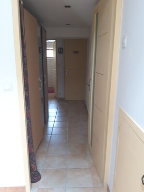 A hallway with doors on both sides, leading to a room with a tiled floor. - A peaceful countryside vacation rental! Perfect for families or friends. Pets Allowed (Cassagnes)