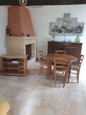 A dining area with a round table and chairs, a fireplace, and a wall with artwork. - A peaceful countryside vacation rental! Perfect for families or friends. Pets Allowed (Cassagnes)