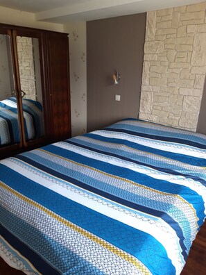 A bedroom with a bed, a wardrobe, a wall-mounted light, and a stone-textured wall. - A peaceful countryside vacation rental! Perfect for families or friends. Pets Allowed (Cassagnes)