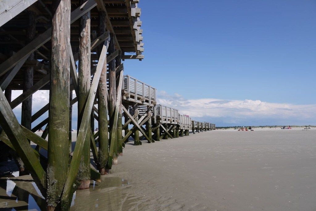 A wooden pier extending into calm waters with a clear sky above.