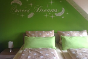 A bedroom with a green wall, a bed with a patterned bedspread, and pillows with star patterns. - Holiday apartment in Bad Harzburg with Wi-Fi (Bad Harzburg)