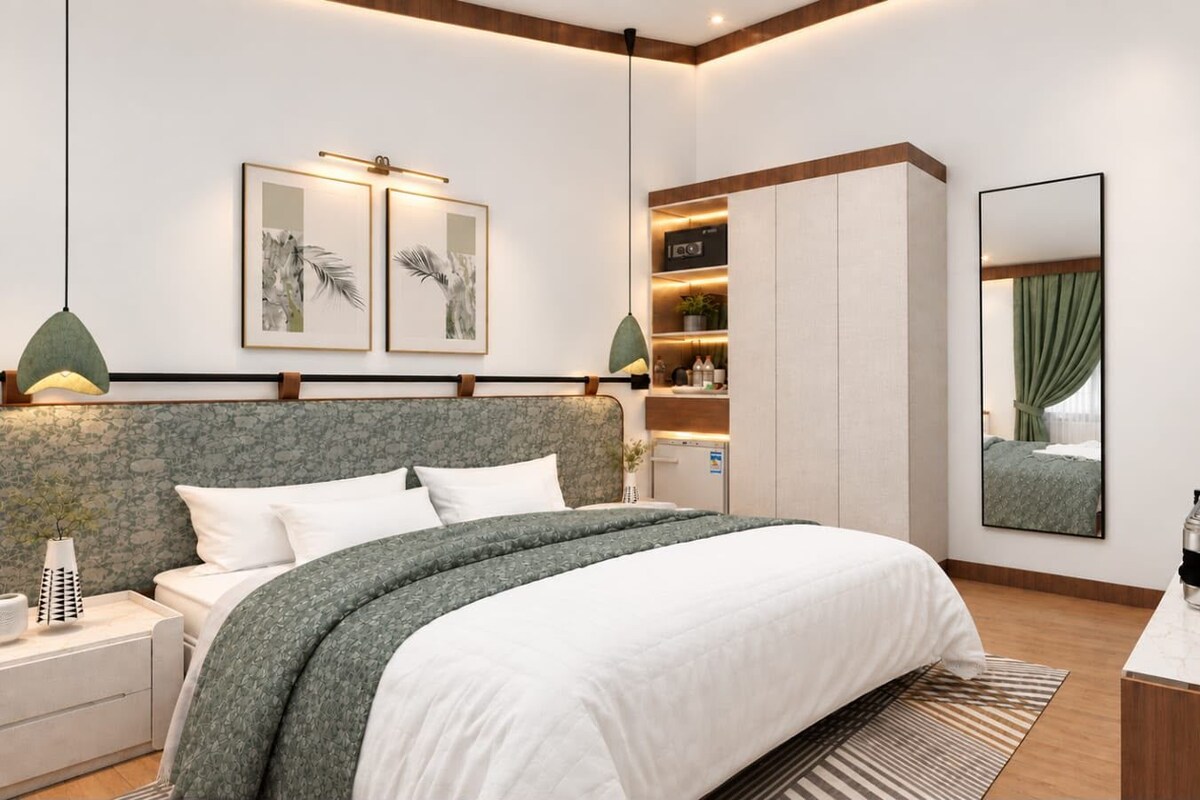 A modern bedroom with a large bed, bedside tables, a wardrobe, a flat-screen TV, and artwork on the walls.