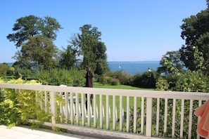 A view from a balcony with a white railing, overlooking a well-maintained garden and a body of water. - Holiday home with 2 bedrooms (Gollenshausen \/Gstadt)