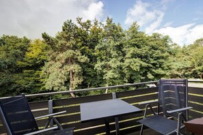 An outdoor seating area with metal chairs and tables, overlooking a dense forest. - Holiday apartment with 2 bedrooms (Sankt Peter-Ording)