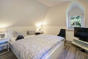 A bedroom with a bed, bedside tables, a TV, and a window. - Holiday apartment with 2 bedrooms (Sankt Peter-Ording)