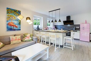 A modern kitchen with a central island, white chairs, and a pink refrigerator. - Holiday apartment with 1 bedroom (Sankt Peter-Ording)