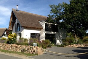 A modern building with a sloped roof, stone wall, and a paved driveway. - Karlshagen beach house (Karlshagen)