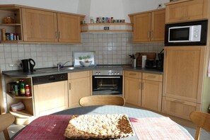 A kitchen with wooden cabinets, a microwave, an oven, and a dishwasher. - Holiday home with 4 bedrooms (Norden \/ Norddeich)