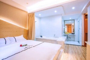A hotel room with a large bed, a bathroom with a bathtub, and a mirror. - Haihao Business Hotel (Chongqing)