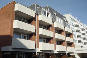 A multi-story residential building with balconies, brick facade, and a clear sky. - Apartment in Westerland with swimming pool (Westerland)