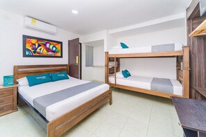 A hotel room with a single bed, a bunk bed, a wooden dresser, a desk, and a colorful abstract painting on the wall. - Hotel Ayenda Casa Paraiso 1327 (Barranquilla)
