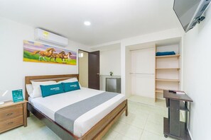 A hotel room with a bed, a nightstand, a desk, a TV, a wardrobe, and a painting of horses. - Hotel Ayenda Casa Paraiso 1327 (Barranquilla)