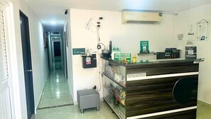 A reception area with a reception desk, a small seating area, and a hallway leading to other rooms. - Hotel Ayenda Casa Paraiso 1327 (Barranquilla)