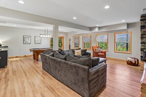 A spacious living room with a large grey sectional sofa, a pool table, and a fireplace. - Ski, Relax & Unwind—6BR Retreat Near Wisp (McHenry)