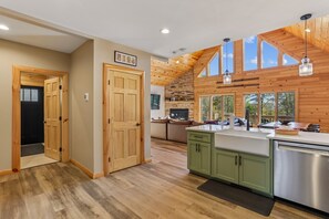 Una cocina moderna con vigas de madera, una chimenea de piedra y un amplio ventanal con vistas al exterior.