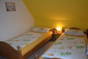 A bedroom with two single beds, each with a floral bedspread and matching pillows. There is a nightstand with a lamp between the beds. - Holiday apartment Strandglück (Hooksiel)