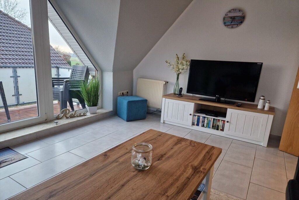 A modern living room with a large TV, a coffee table, and a bookshelf.