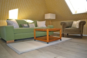 A room with a green sofa, a brown armchair, a wooden coffee table, and a lamp. - Beach grass - directly in Wyk (Wyk\/Föhr)