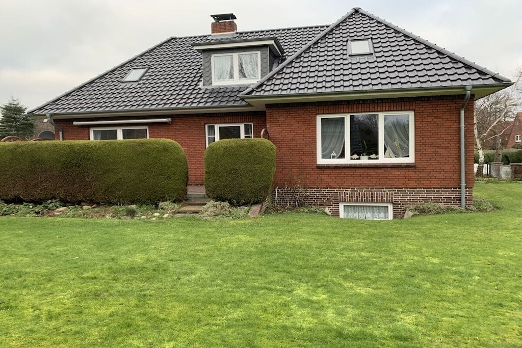 Ein zweigeschossiges Haus mit Ziegeldach, einem kleinen Fenster mit weißem Rahmen und einem gepflegten Rasen.