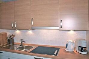 A kitchen with wooden cabinets, a stainless steel sink, a kettle, and a coffee maker. - Beach grass - directly in Wyk (Wyk\/Föhr)