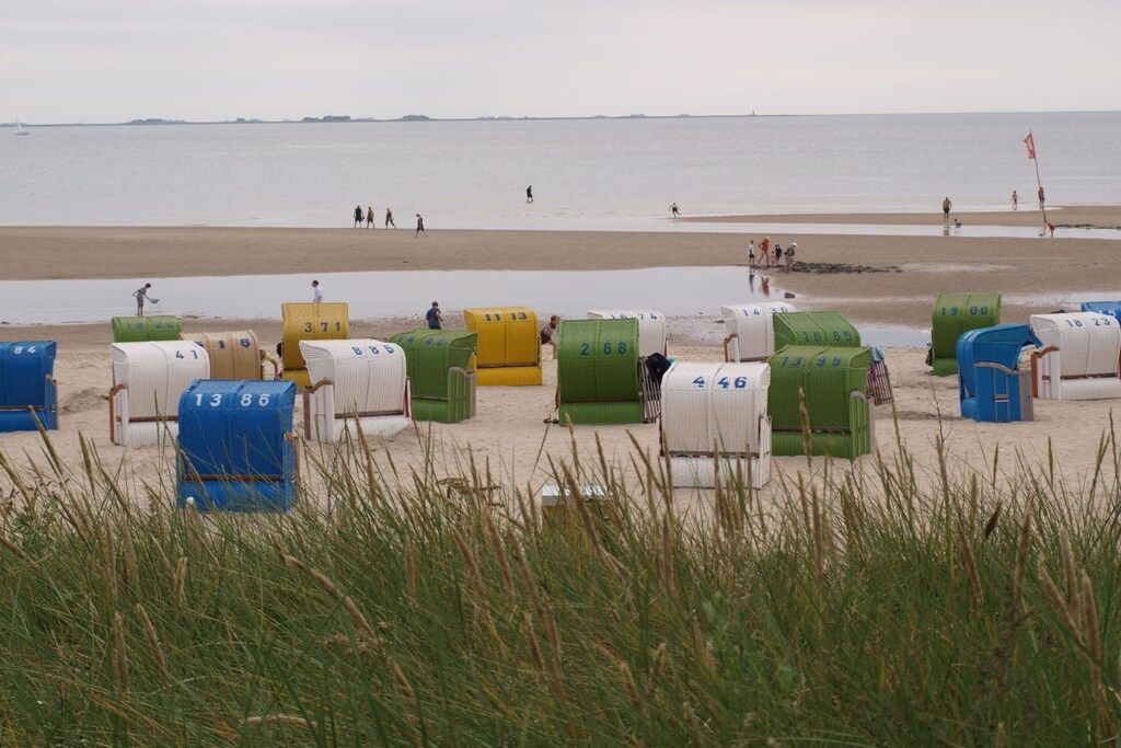 A beach with numbered beach huts and a calm sea in the background.