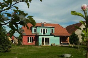 A two-story house with a red roof and a blue exterior. There is a lawn in front of the house. - Holiday home in Hitzacker with Wi-Fi (Hitzacker)